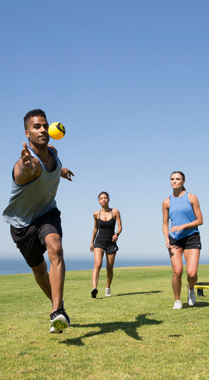 芝生でボールを使って運動をしている2人の女性と1人の男性